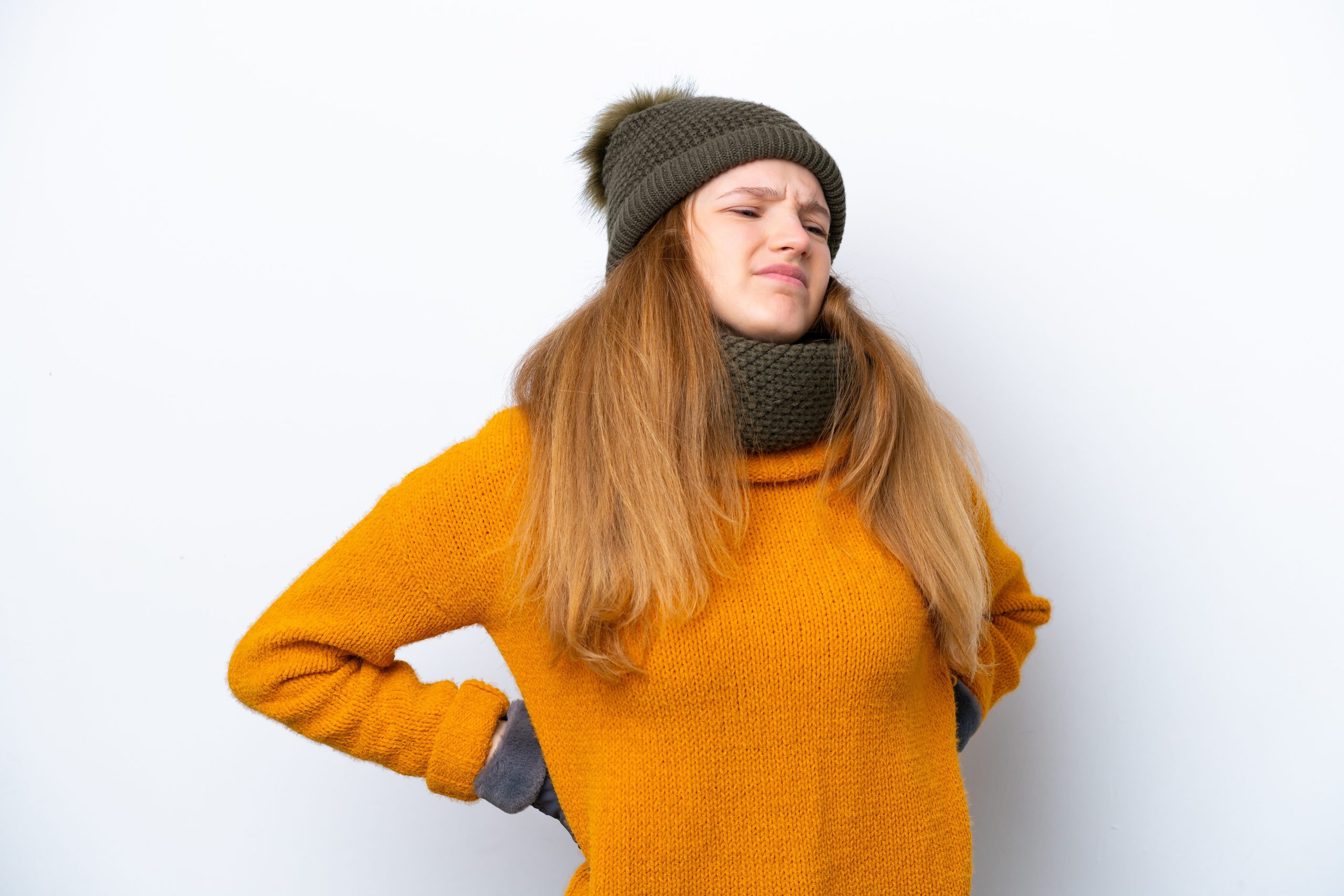 Teenage girl wearing winter jacket isolated on white background suffering from back pain due to weather changes